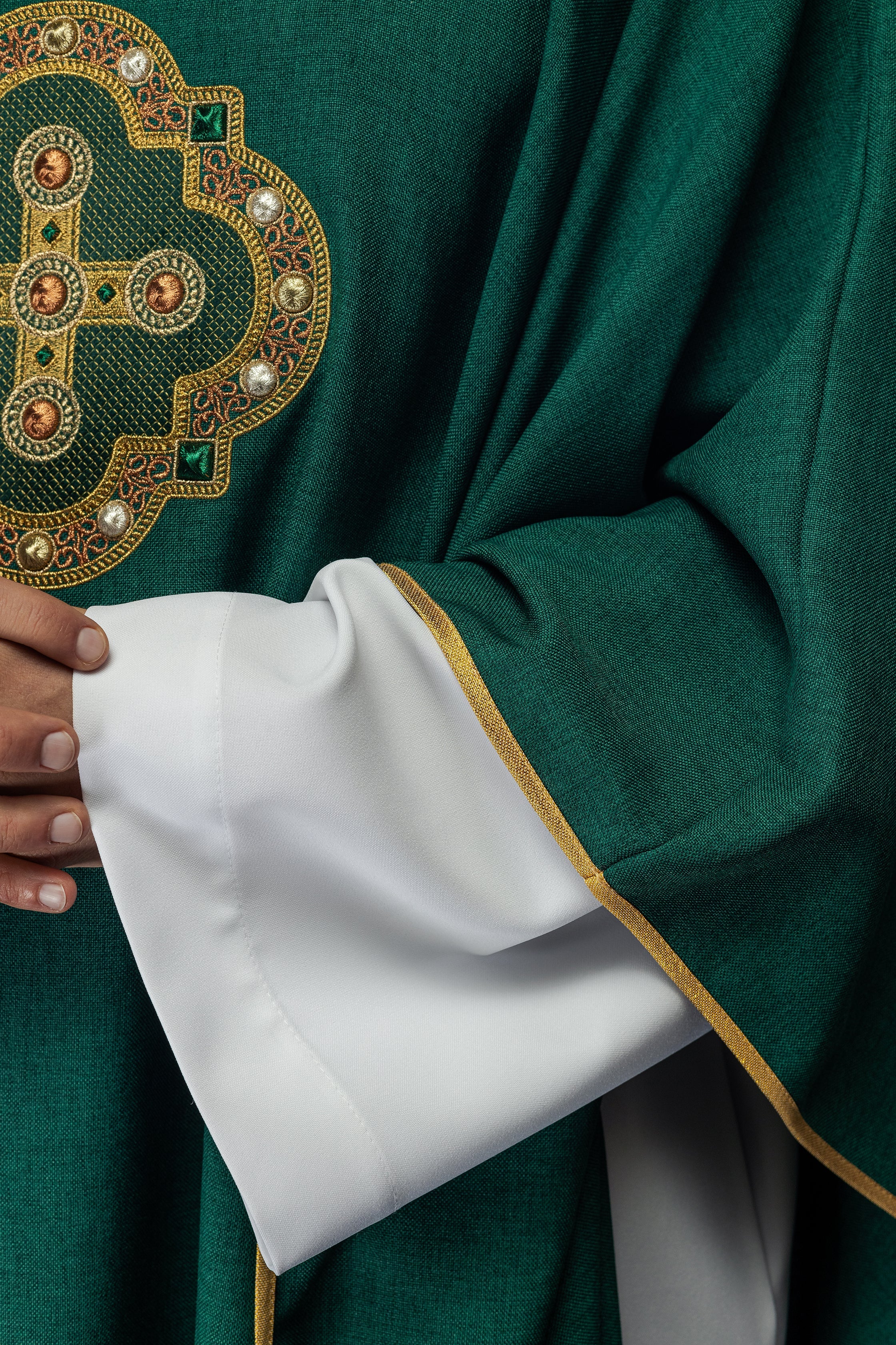 Casulla de color verde con ribetes bordados en el cuello y alrededor del bordado de la cruz